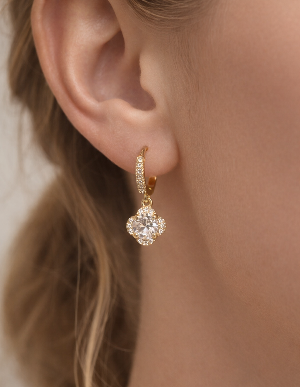Close-up of a gold earring with a diamond on a blurred background