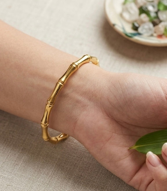 Gold bamboo bracelet on a wrist with a neutral background