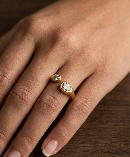 Hand wearing a ring with a heart-shaped diamond on a wooden surface