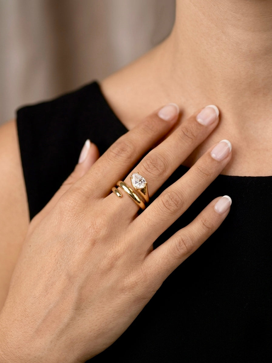 Hand wearing a gold ring with a diamond on a blurred background