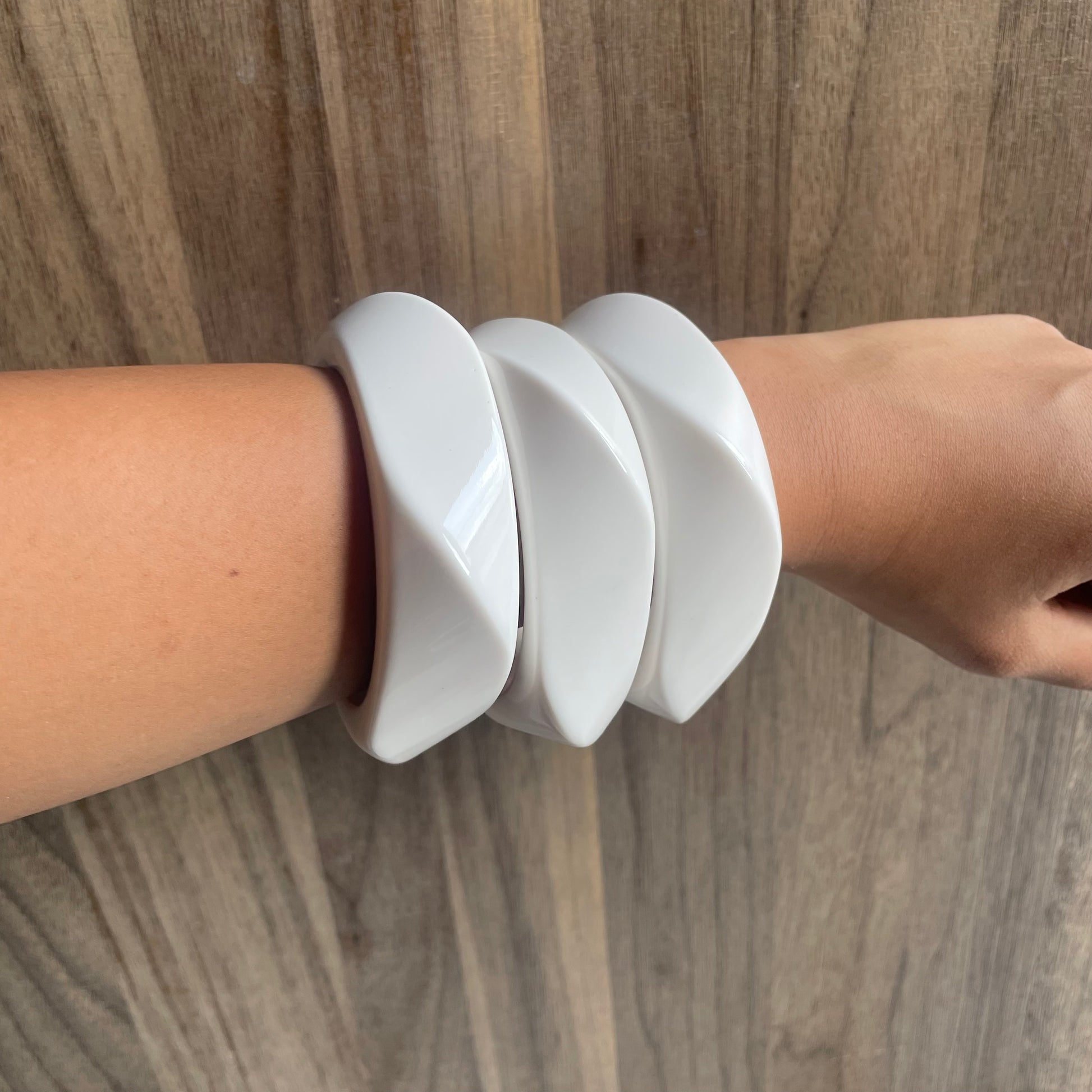 White bracelet on a wrist against a wooden background