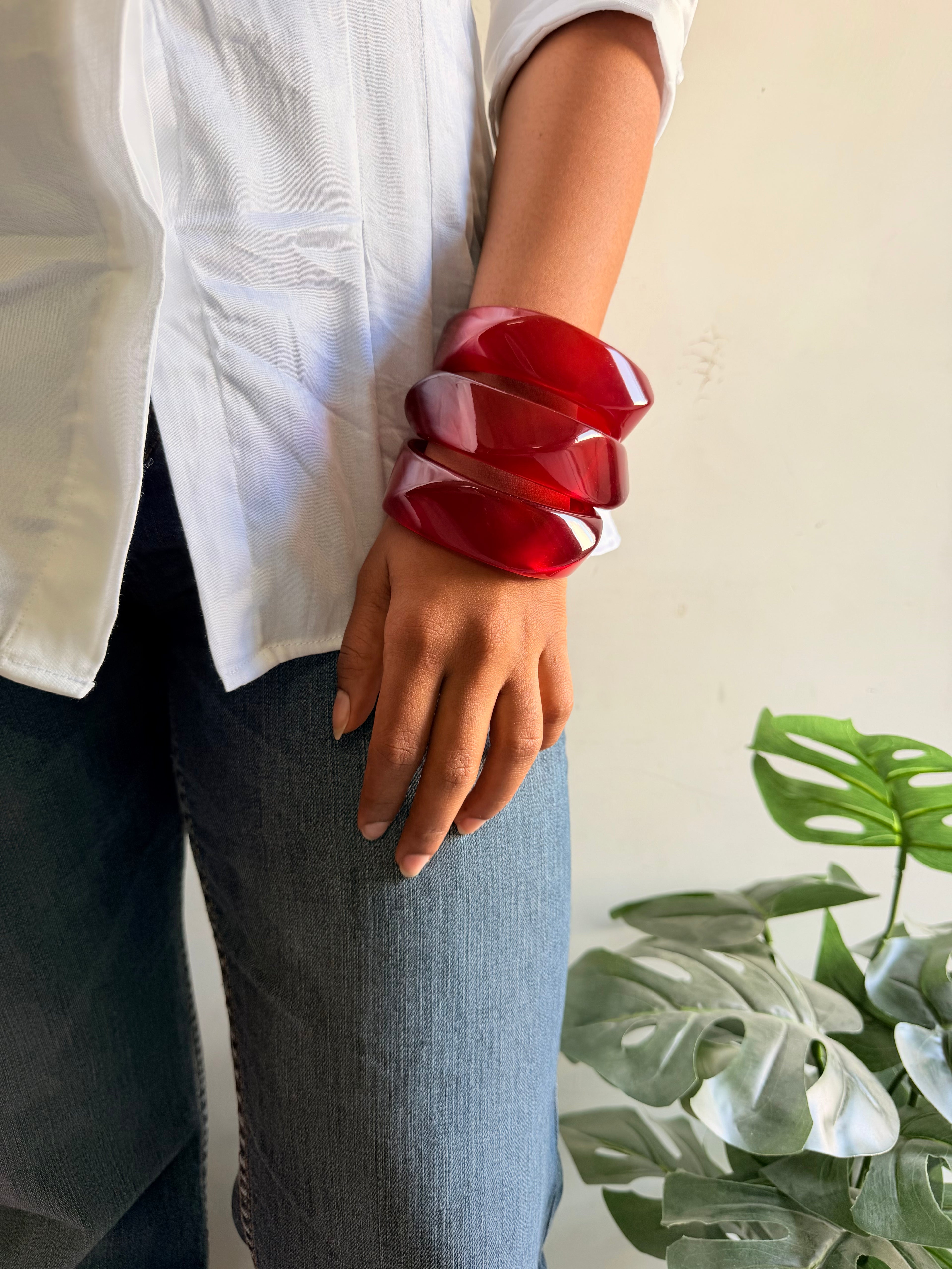 Person wearing a red bracelet with a plant in the background