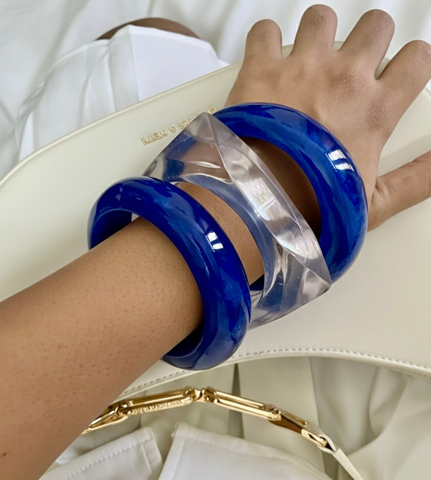 Close-up of a hand wearing blue bangles with a white background