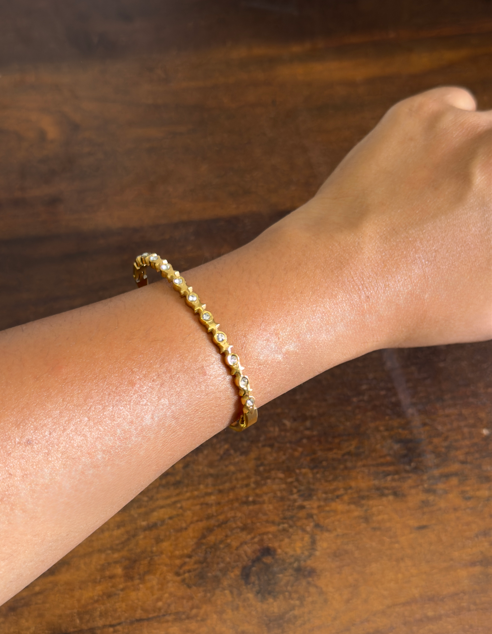 Gold bracelet on a wrist against a wooden background