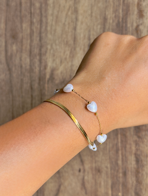 Bracelet with heart-shaped beads on a wrist against a wooden background
