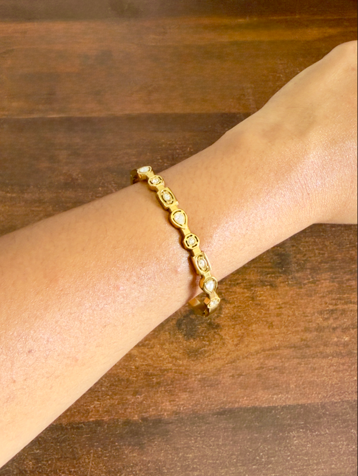 Gold bracelet on a wrist against a wooden background