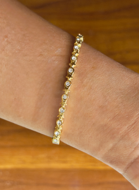 Gold bracelet with small stones on a wrist against a wooden background